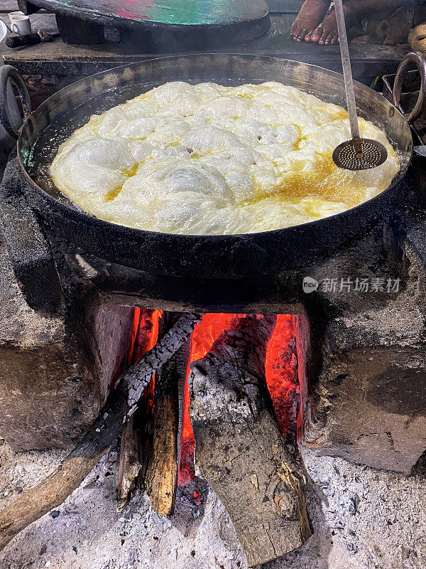 油炸的halwa paratha(小麦粉大饼)，在街头小吃摊的火上煮油的karahi菜(有柄的平底锅)的图像，高视图，重点在前景